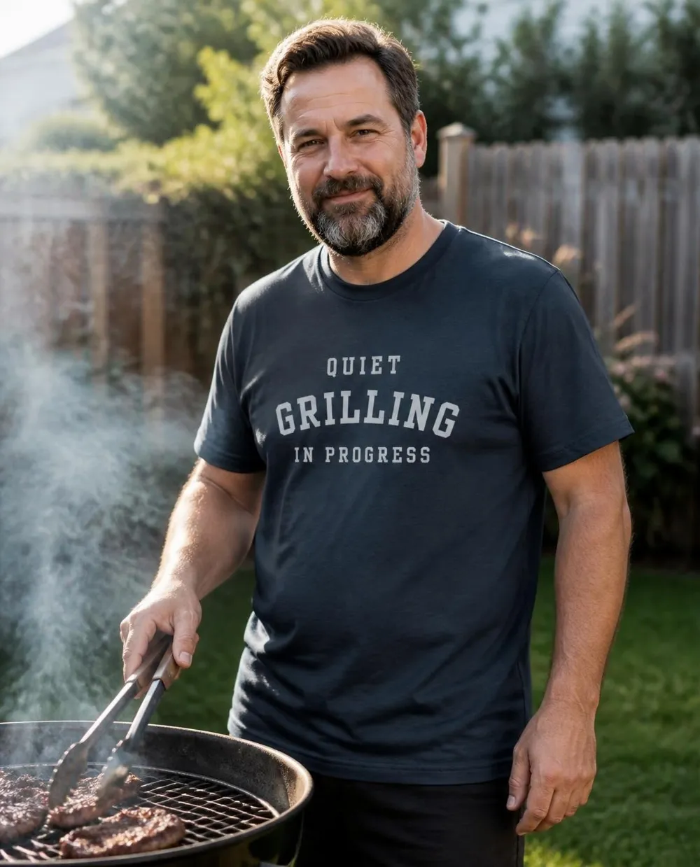 Man at the grill wearing the Quiet, Grilling in Progress tee